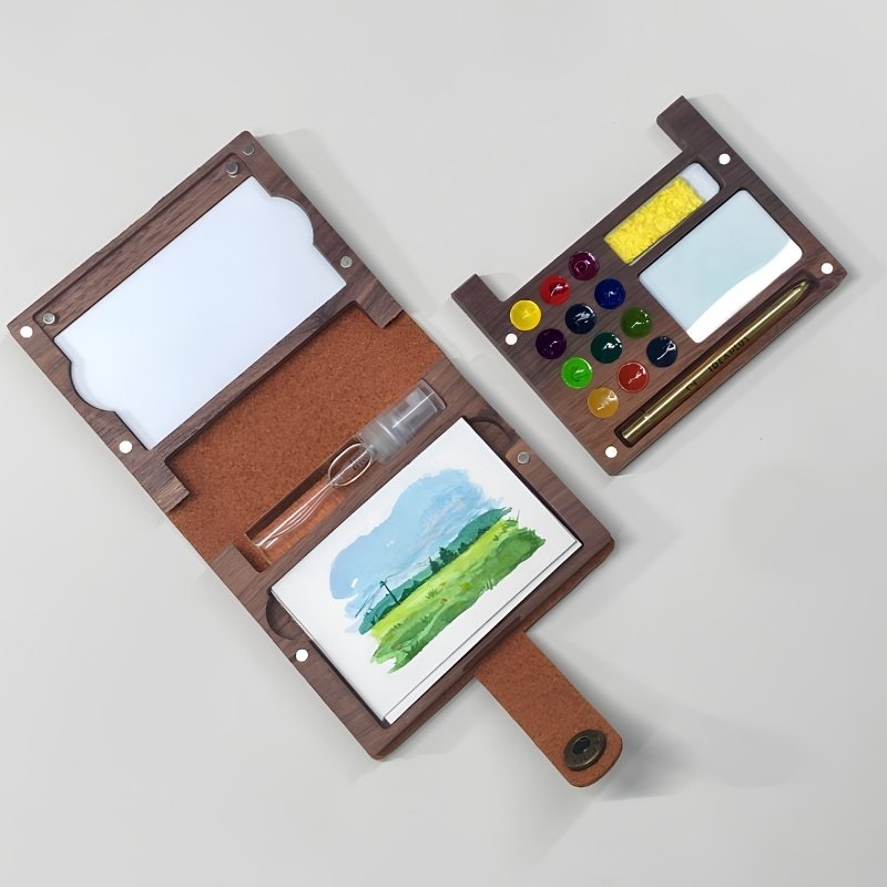 Walnut folio kit open with a detachable palette tray, landscape painting, 12 paints, brush and sponge
